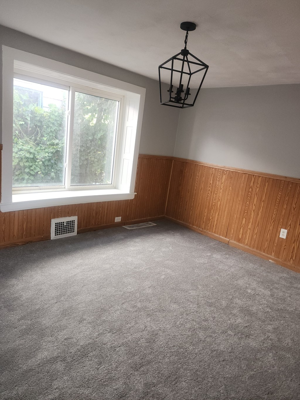 A room with a window and a hanging light fixture.