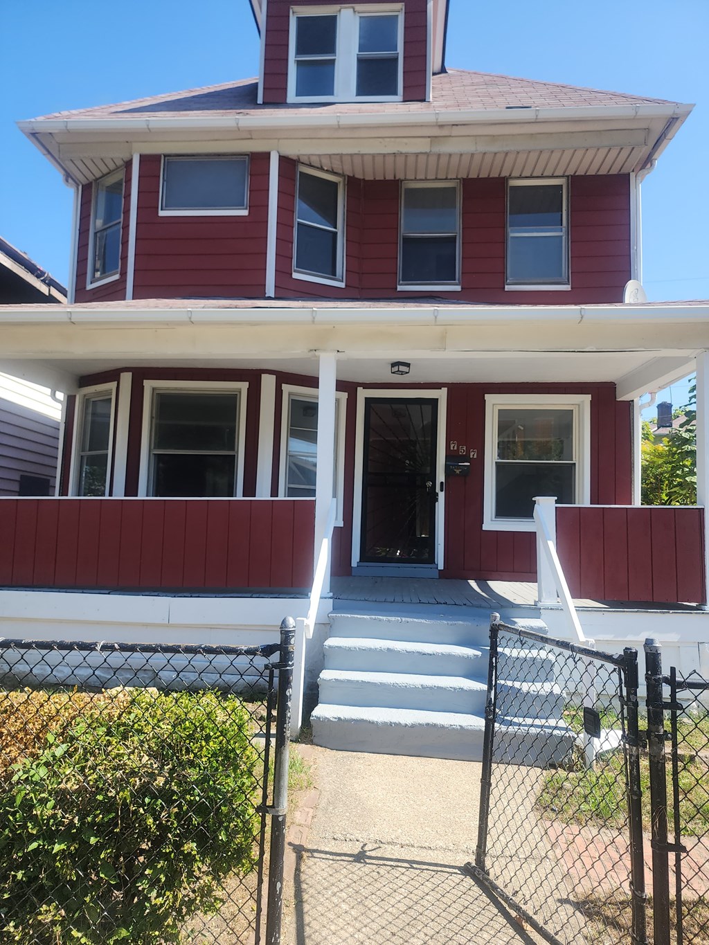A red house with a black fence in front.