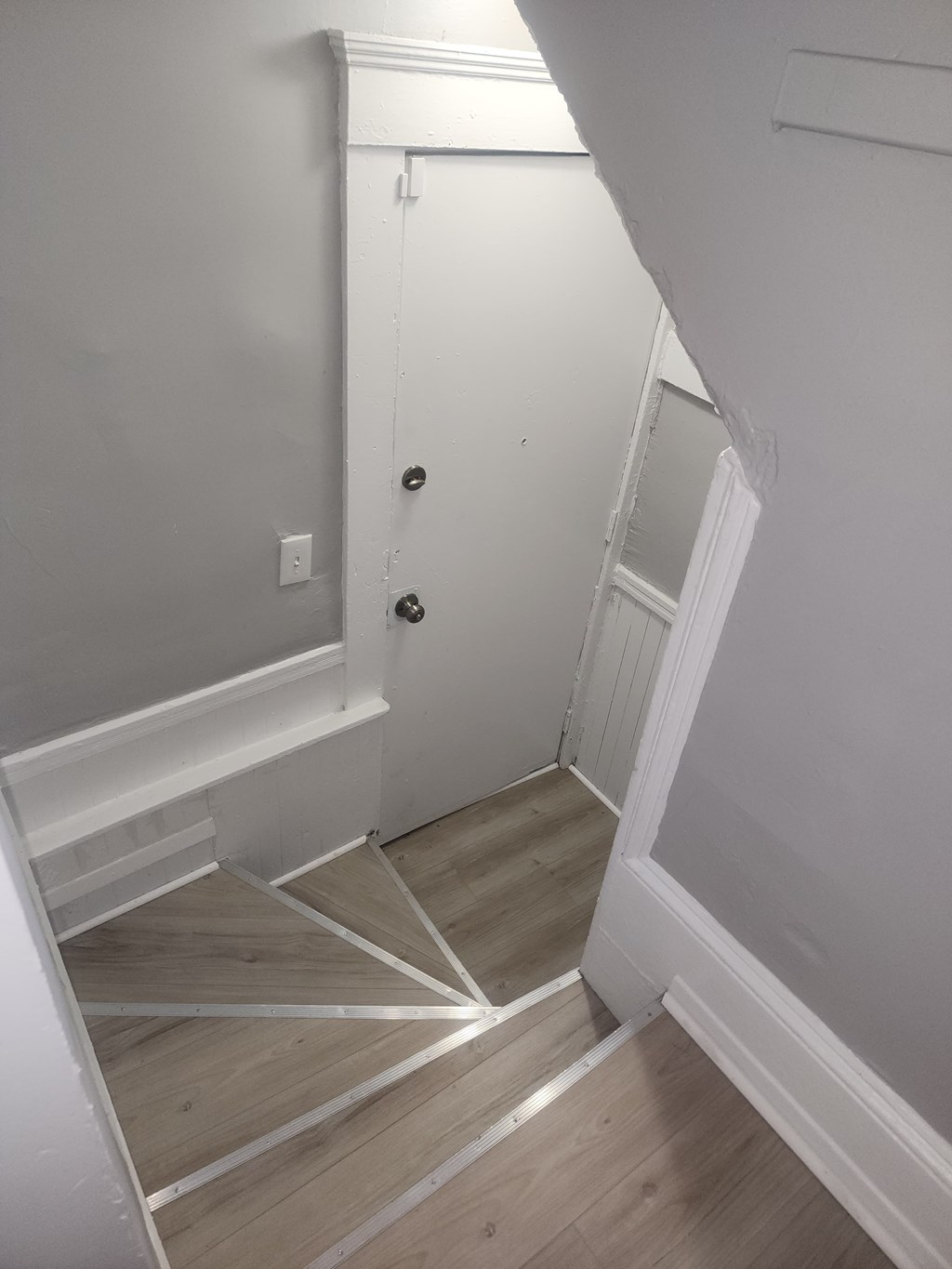 A white door with a black handle is in a white room.