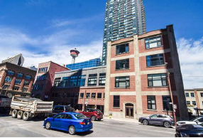 A blue car is parked in front of a red brick building.