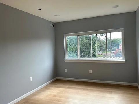 A room with a large window and wooden flooring.