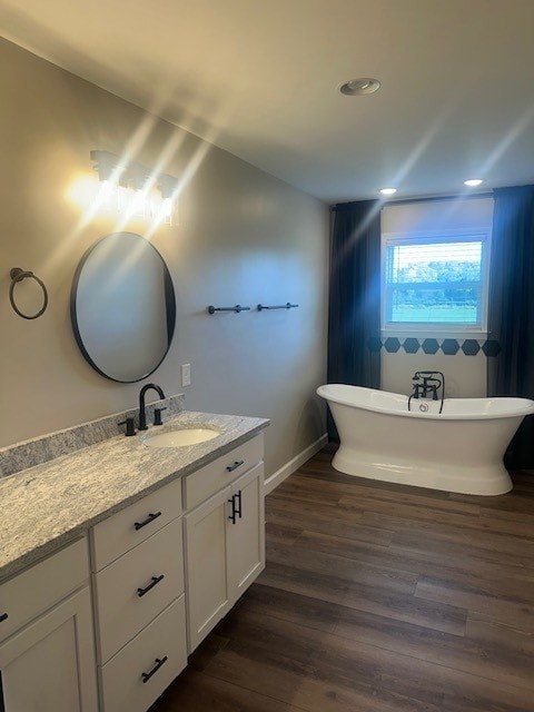 A bathroom with a white tub and a round mirror on the wall.
