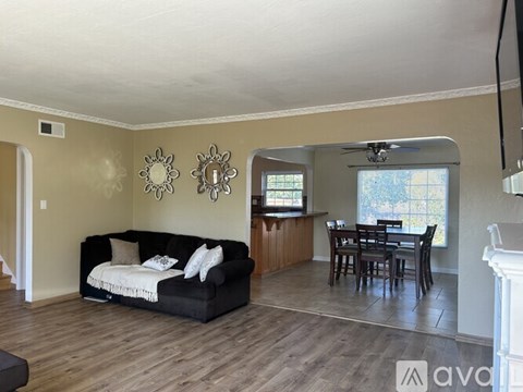 A living room with a black couch and a dining table.