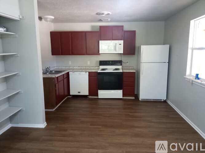 A kitchen with red cabinets and white appliances.