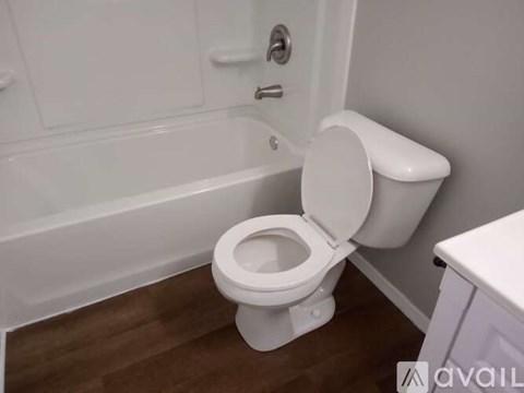 A white toilet is installed in a bathroom with a white tub.
