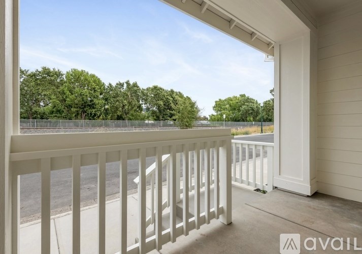 A balcony with a view of a street and trees.