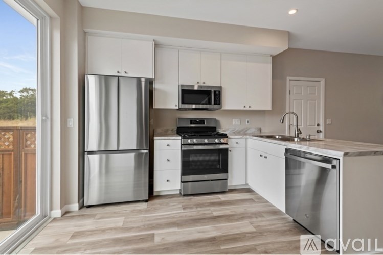 A kitchen with a refrigerator, oven, microwave, and sink.