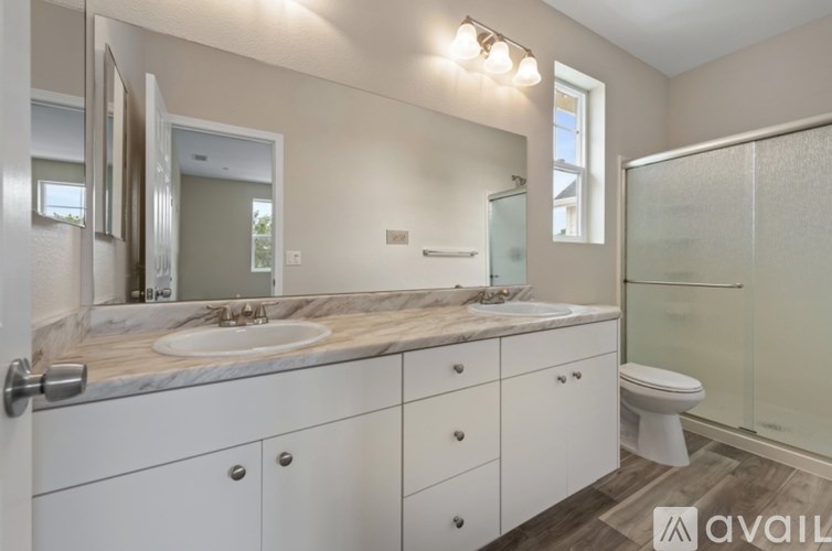 A bathroom with a marble countertop and white cabinets.