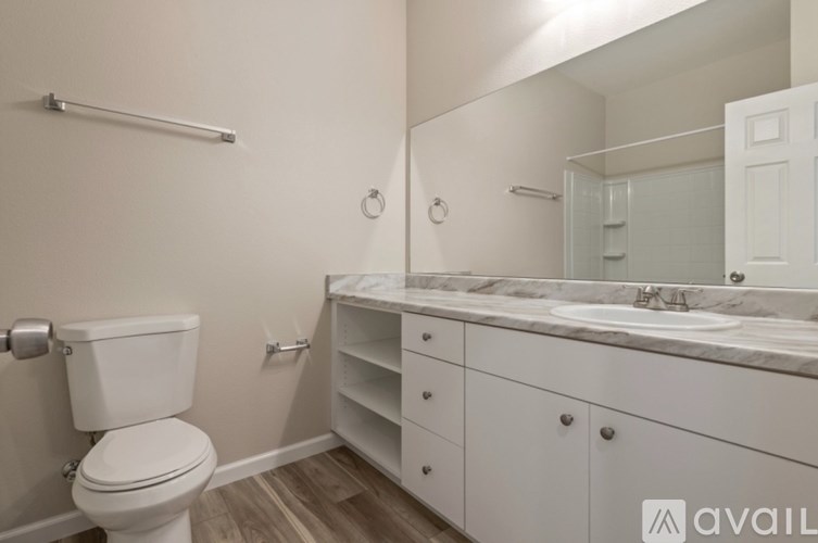 A white bathroom with a toilet, sink, and mirror.