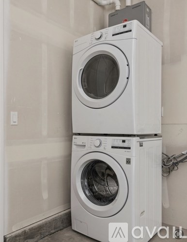 Two white front loading washing machines stacked on top of each other.