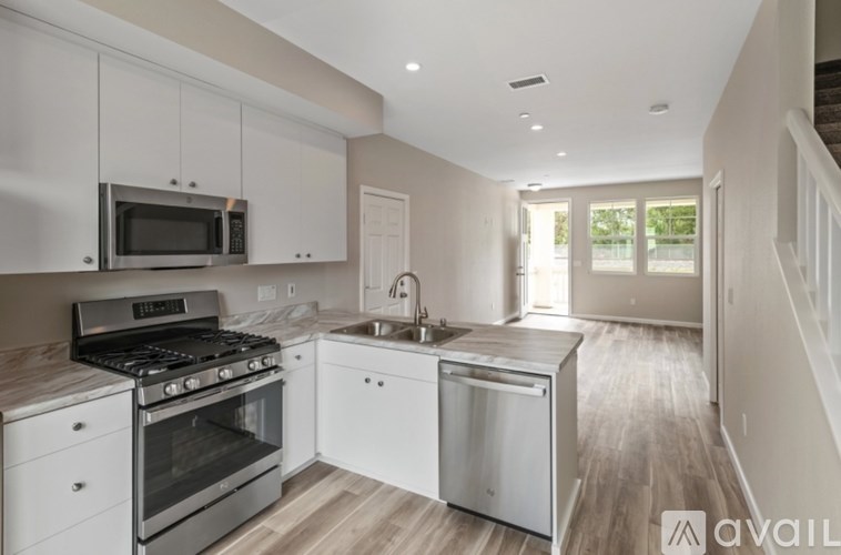 A modern kitchen with white cabinets and stainless steel appliances.