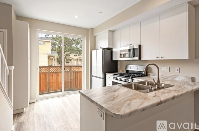 A kitchen with a marble countertop and a black refrigerator.