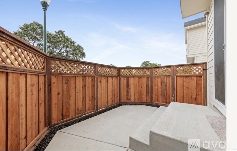 A wooden fence encloses a concrete patio area.
