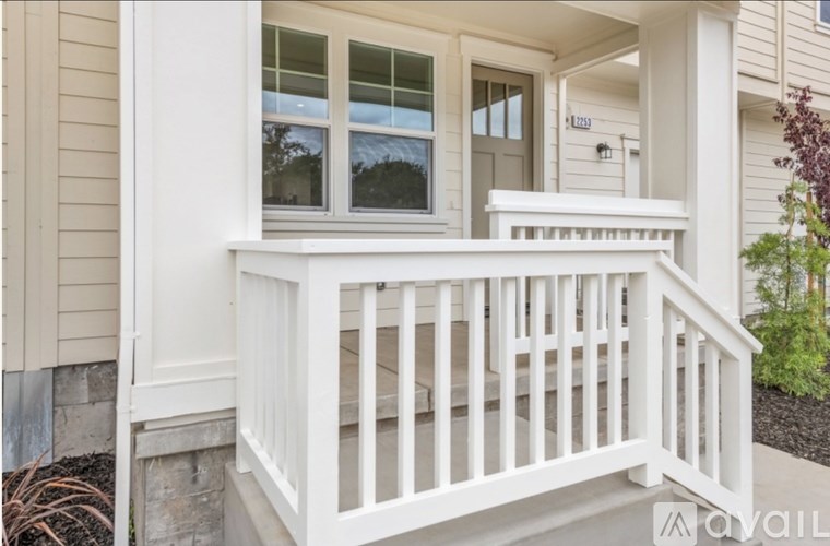 A white porch with a railing and steps leading to a door.