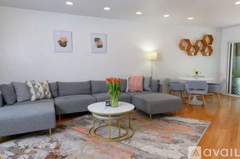 A living room with a grey sofa, a white coffee table, and a rug with a floral pattern.