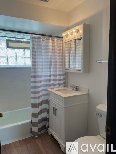 A bathroom with a striped shower curtain and wooden floors.