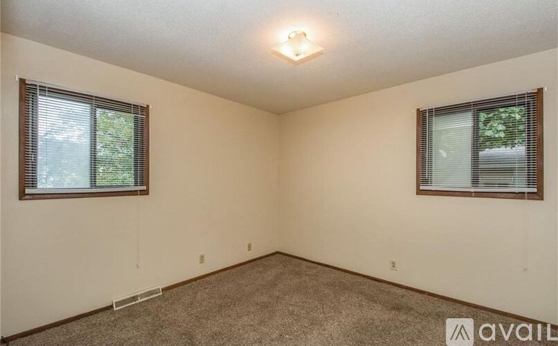 A room with two windows and carpeted floor.