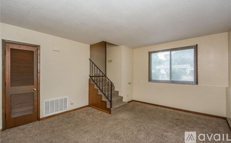 A room with a staircase, a window, and a door.
