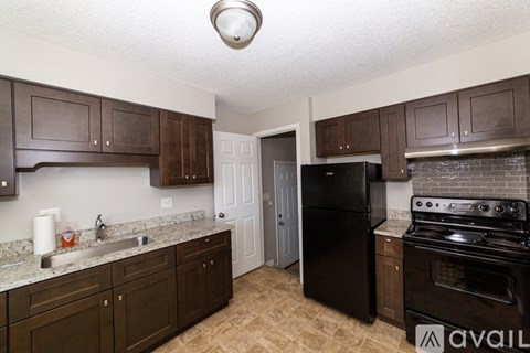 A kitchen with brown cabinets and a black refrigerator.