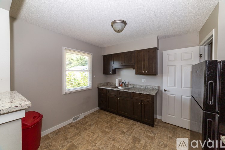 A kitchen with a black fridge, white oven, and brown cabinets.