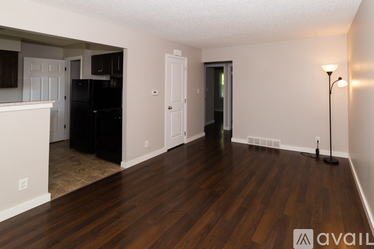 A room with wooden floors and a black refrigerator.