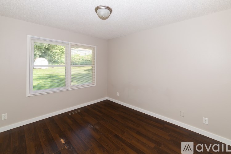 A room with wooden floors and a window with blinds.