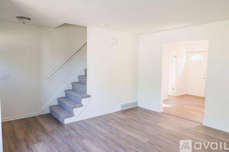 A room with a staircase and a door leading to another room.