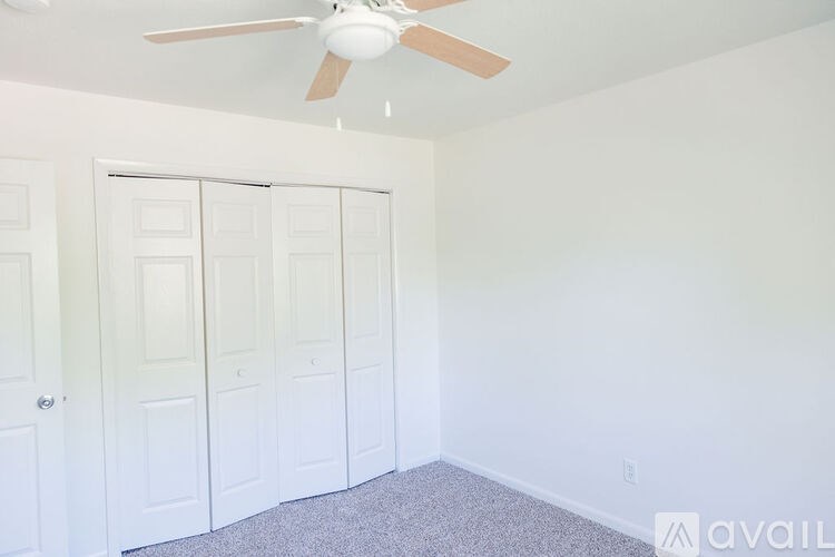 A room with a ceiling fan and a wall of doors.