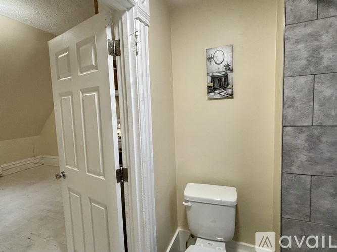 A bathroom with a toilet and a painting on the wall.