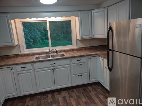 A kitchen with white cabinets and a stainless steel refrigerator.