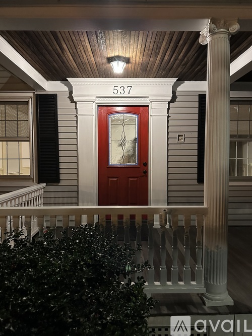 A white house with a porch and a brown door.