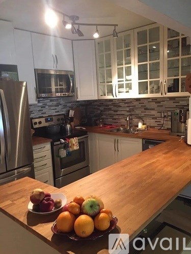 A kitchen with a wooden countertop and a bowl of fruit on it.