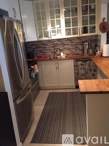 A kitchen with a stainless steel refrigerator and wooden countertops.