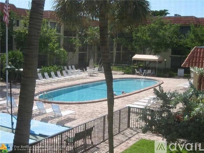 A pool surrounded by palm trees and chairs.