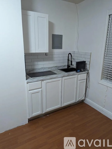 A kitchen with white cabinets and a black laptop on the counter.