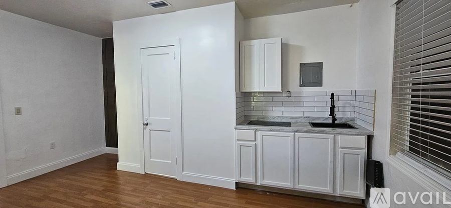 A kitchen with white cabinets and a black countertop.