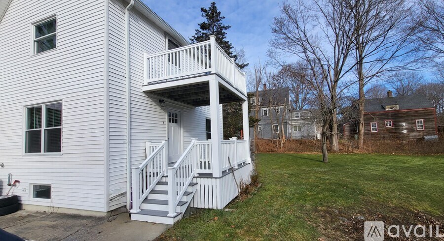 A white house with a balcony and stairs leading to the balcony.