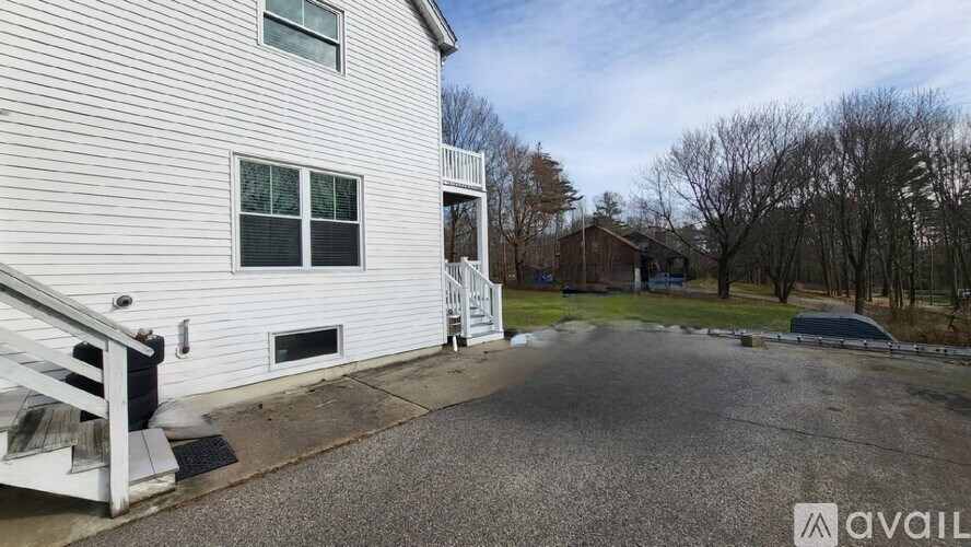 A white house with a gravel driveway in front.