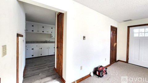 A kitchen with white cabinets and a wooden door.