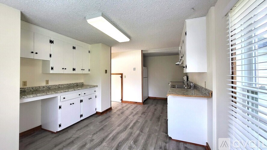 A kitchen with white cabinets and a granite countertop.