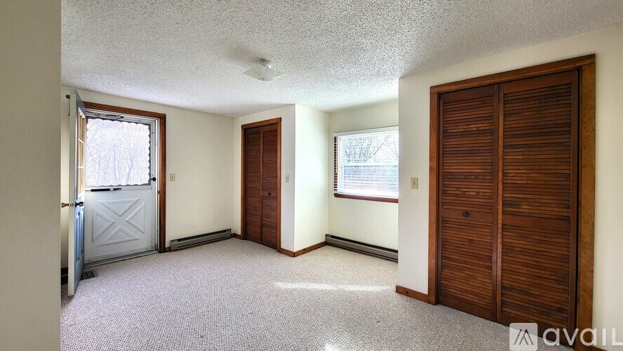 A room with a carpeted floor and a ceiling fan.