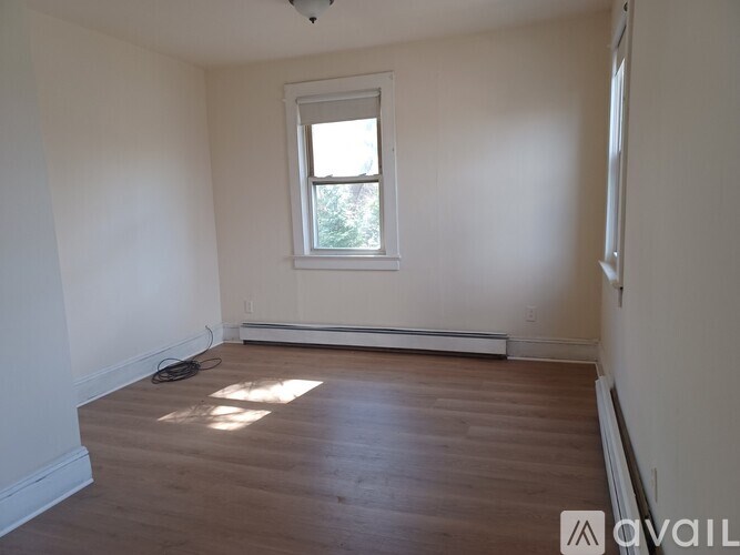 A room with a window and a wooden floor.