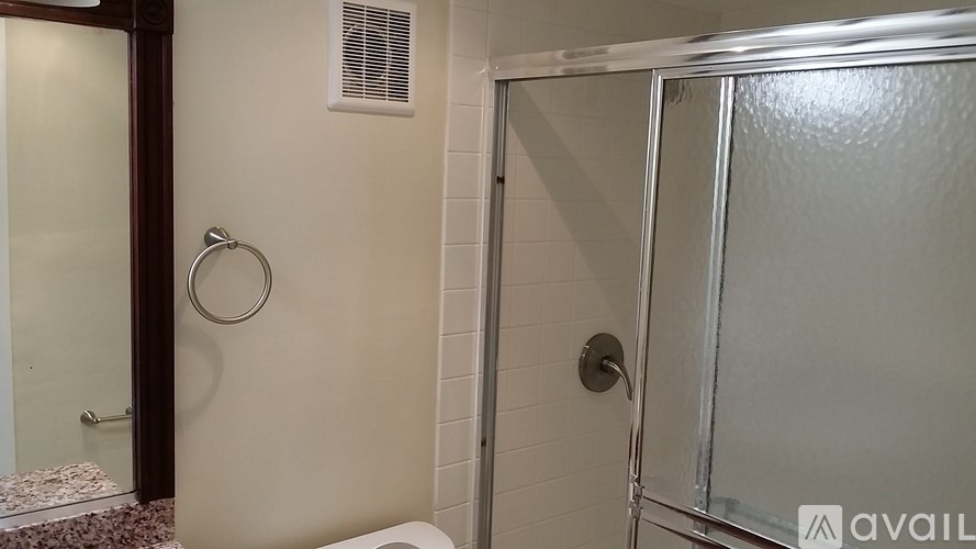 A bathroom with a glass shower door and a towel rack.