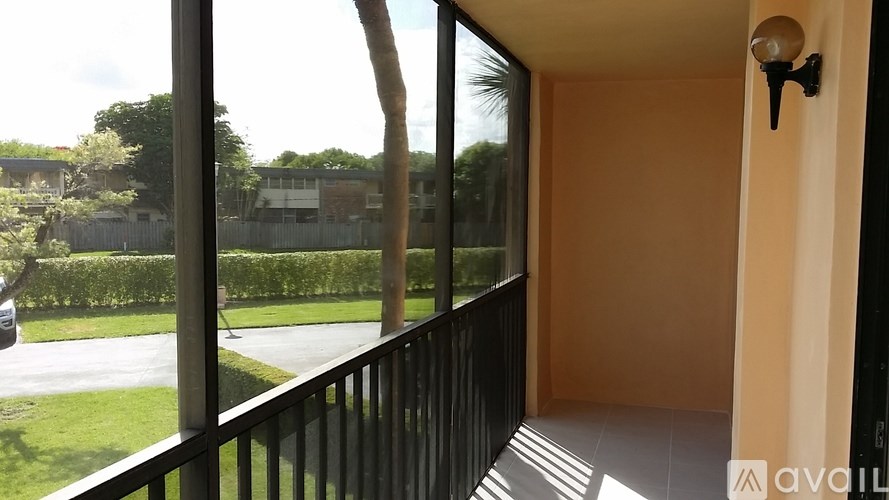 A balcony with a black railing and a view of a street and houses.