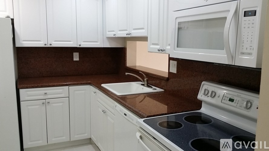 A kitchen with white cabinets and brown countertops.