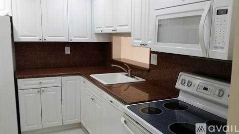 A kitchen with white cabinets and brown countertops.