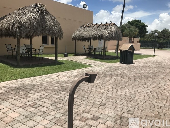 A patio with a thatched roof and a brick floor.