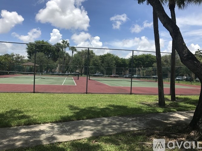 A tennis court surrounded by a fence and trees.