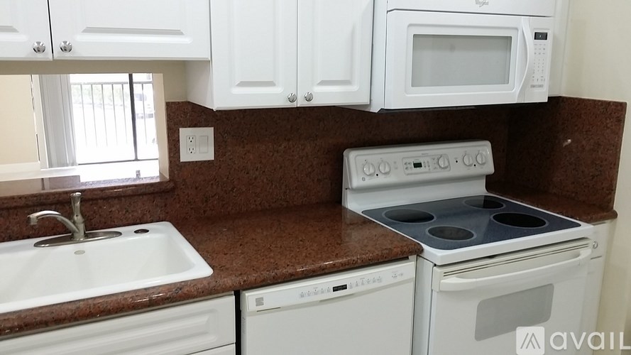 A kitchen with white appliances and brown countertops.