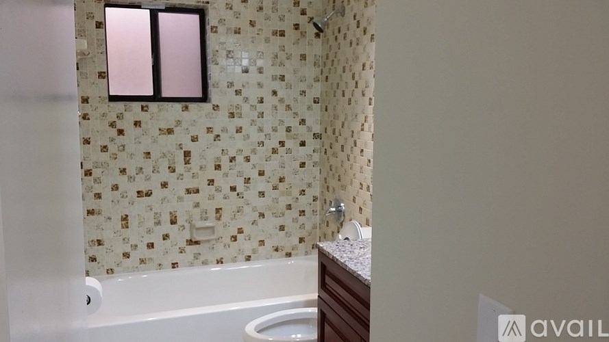 A bathroom with a tiled wall and a bathtub.